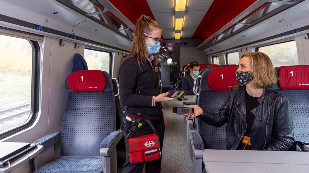 Des voyageurs et une contrôleuse portant un masque dans le train.